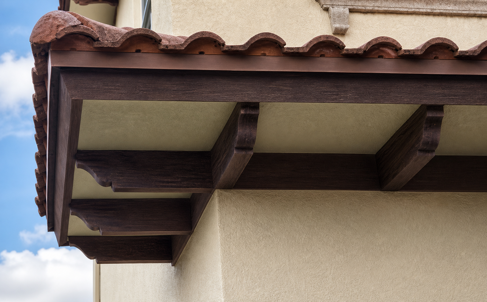 Wood-look decorative corbels beneath a tiled roof overhang